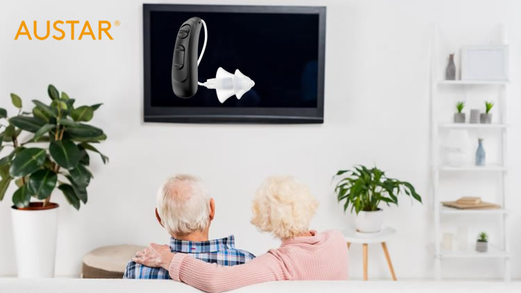 Couple wearing hearing aids watching TV